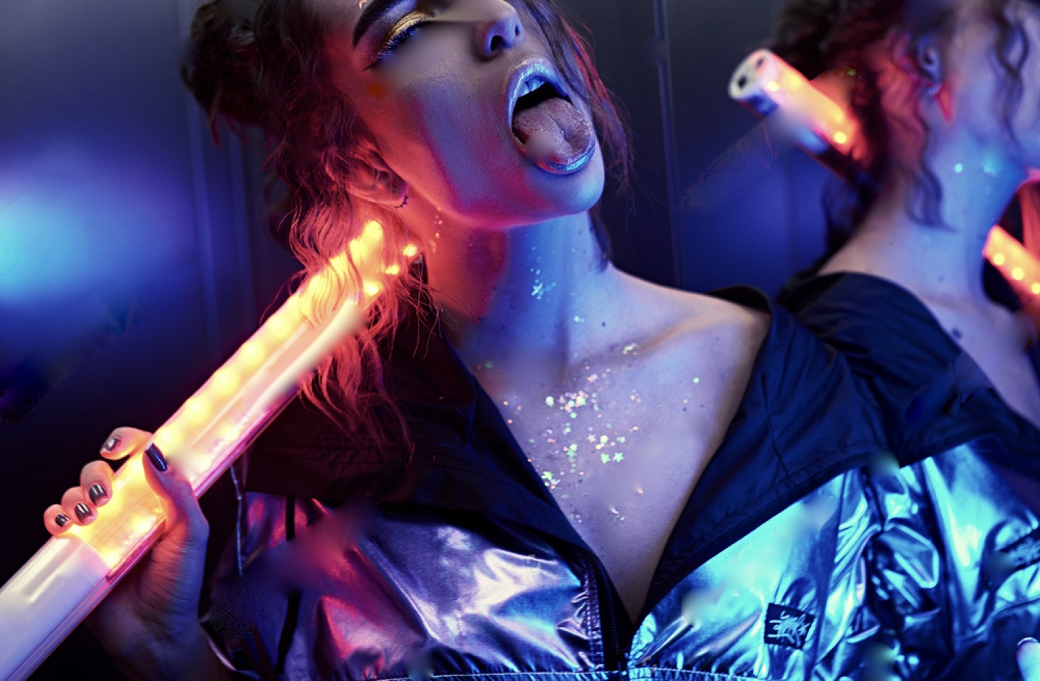 Beautiful Woman with Sparkles on Her Face in Ultraviolet Light Showing Her Tongue with Silly Face